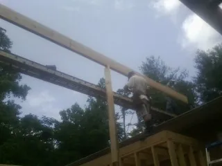 Carpenter setting a ridge beam over a new addition frame — Ice Dam Removal by Roofing Brothers in Dedham