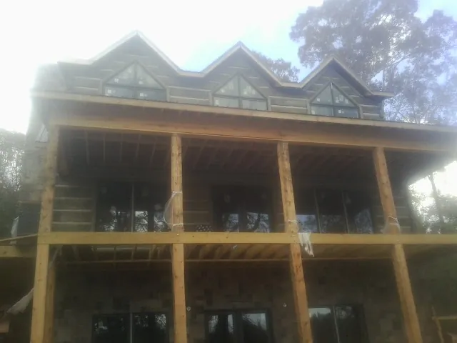 Dormers and porch framing on a large log home under construction — Roof Coating work by our crew in Dedham